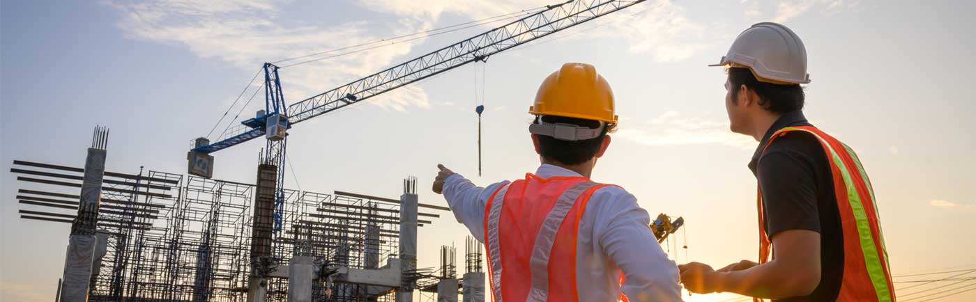 Two construction workers overseeing an on site infrastructure project.