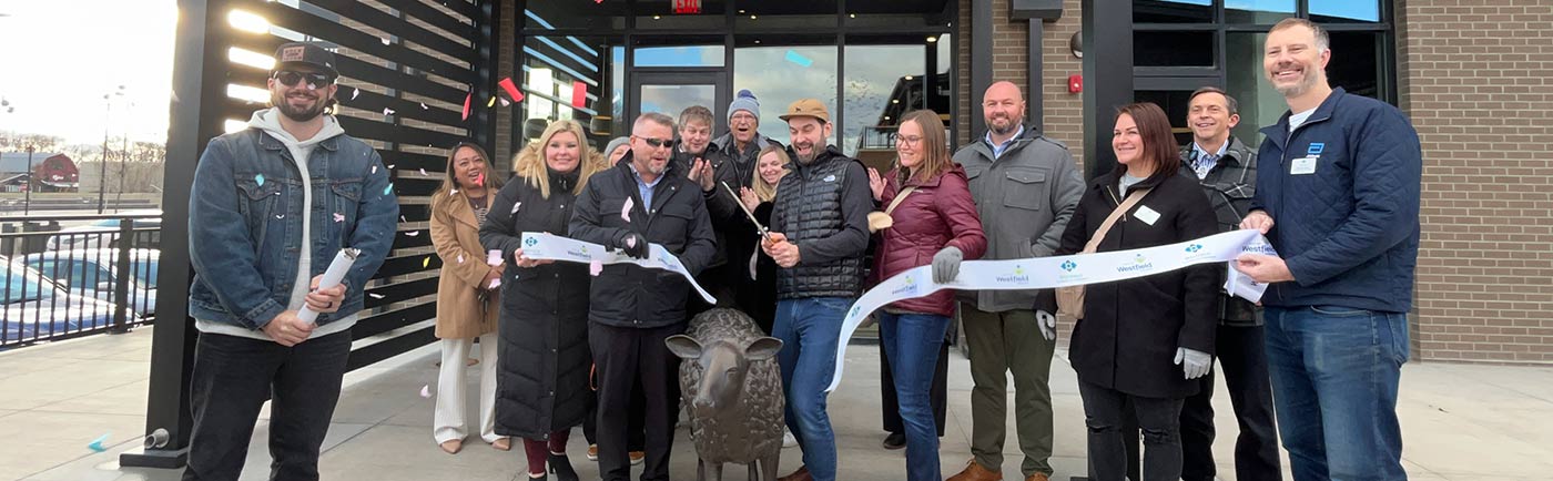 A group gathers for a ribbon-cutting ceremony at BLACKSHEEP