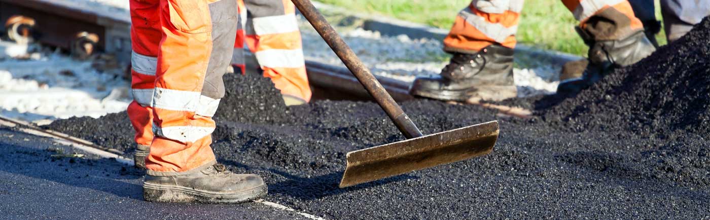 Construction worker laying hot asphalt on a road